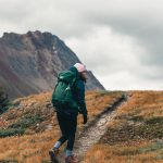 woman with backpack climbing up the mountain