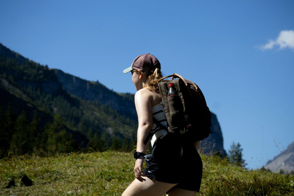 hiker walking uphill trail in the countryside carrying a backpack