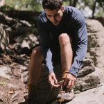 a man in a long sleeved shirt tying his shoes
