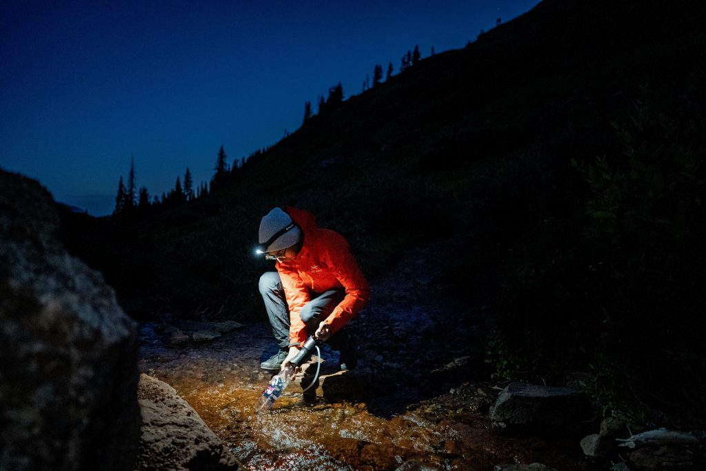 hiker filtering stream water while wild camping in the UK
