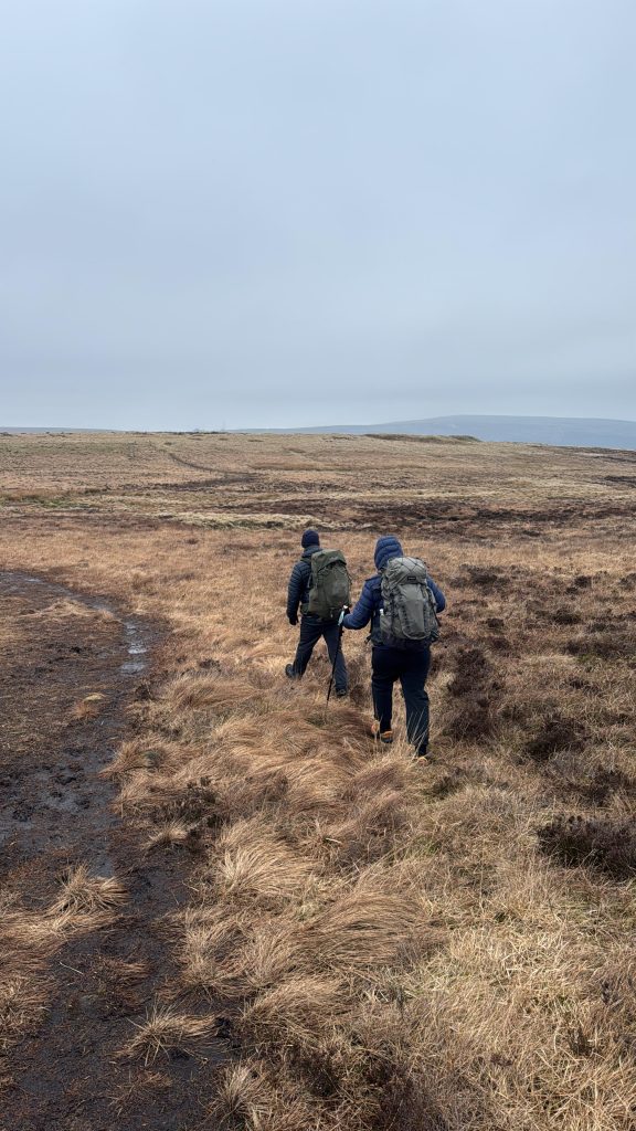 hiker carrying a large backpack while wild camping in the UK hills
