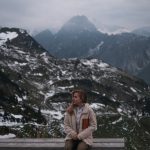 woman sitting on bench in snowy mountain landscape