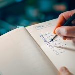 writing in notebook with checklist for task management