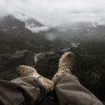 Hiker wearing walking trousers and boots overlooking a misty mountain valley